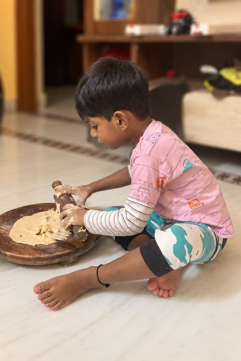 Child rolling and kneading dough during a hands-on sensory play activity at home.