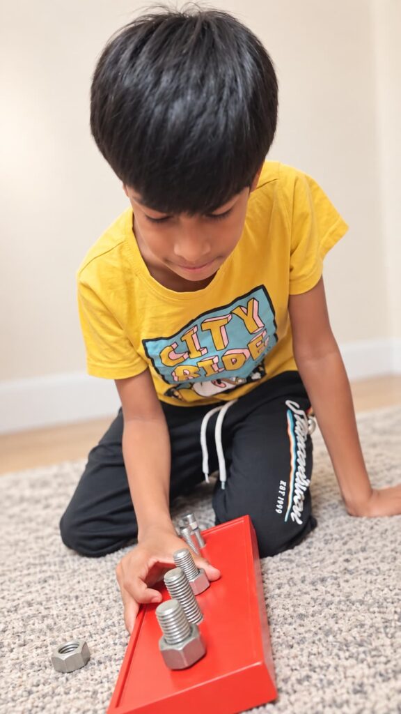 Child completing a hands-on learning activity using nuts and bolts during play.