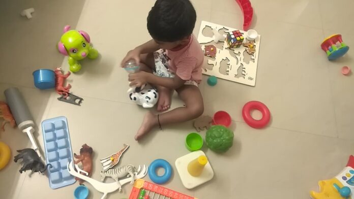 Toddler playing independently with educational toys during early childhood development.