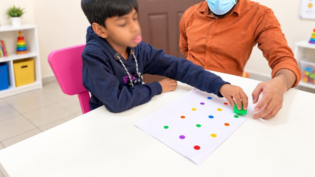 Child participating in a structured colour-matching activity with guidance from a therapist.